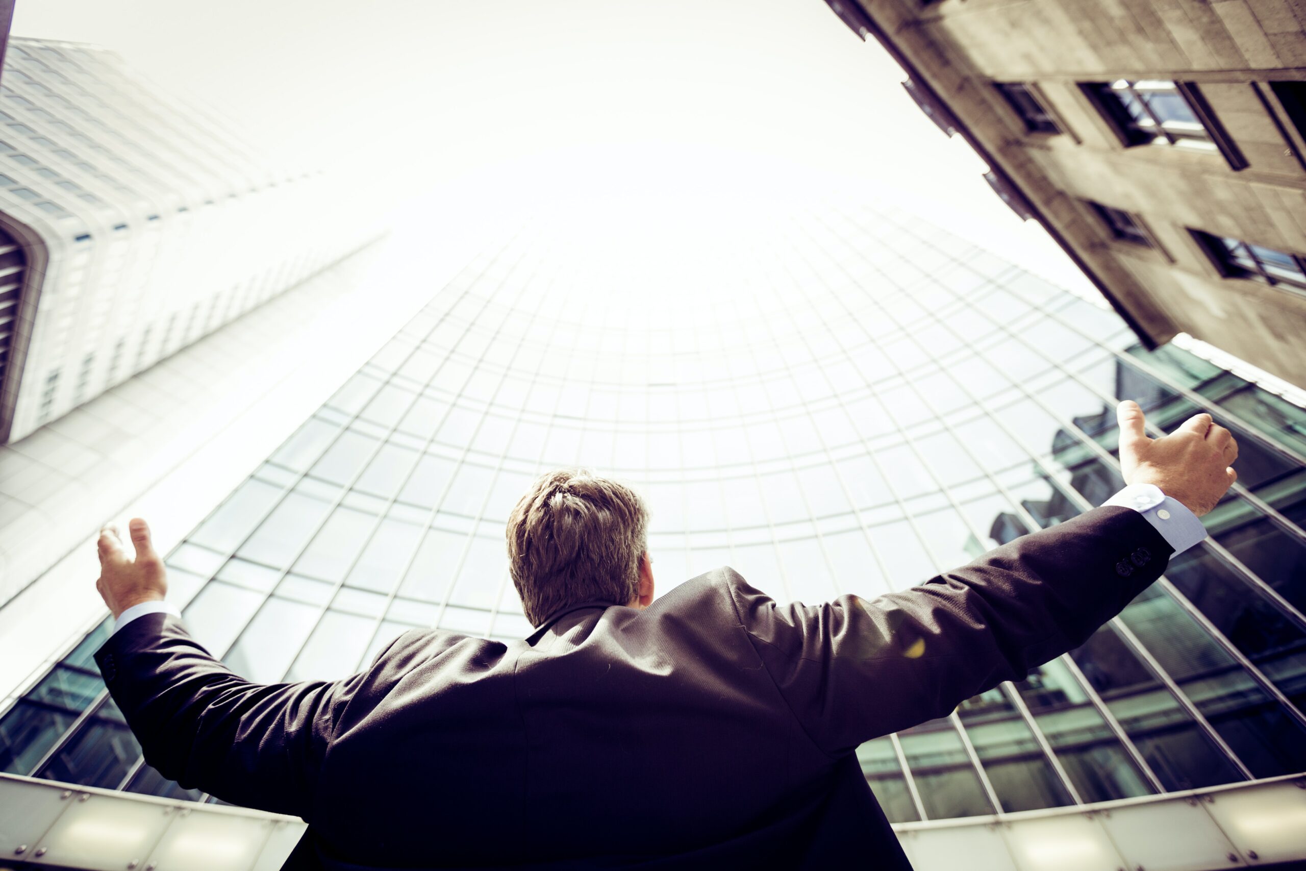 man next to a building holding his arms out