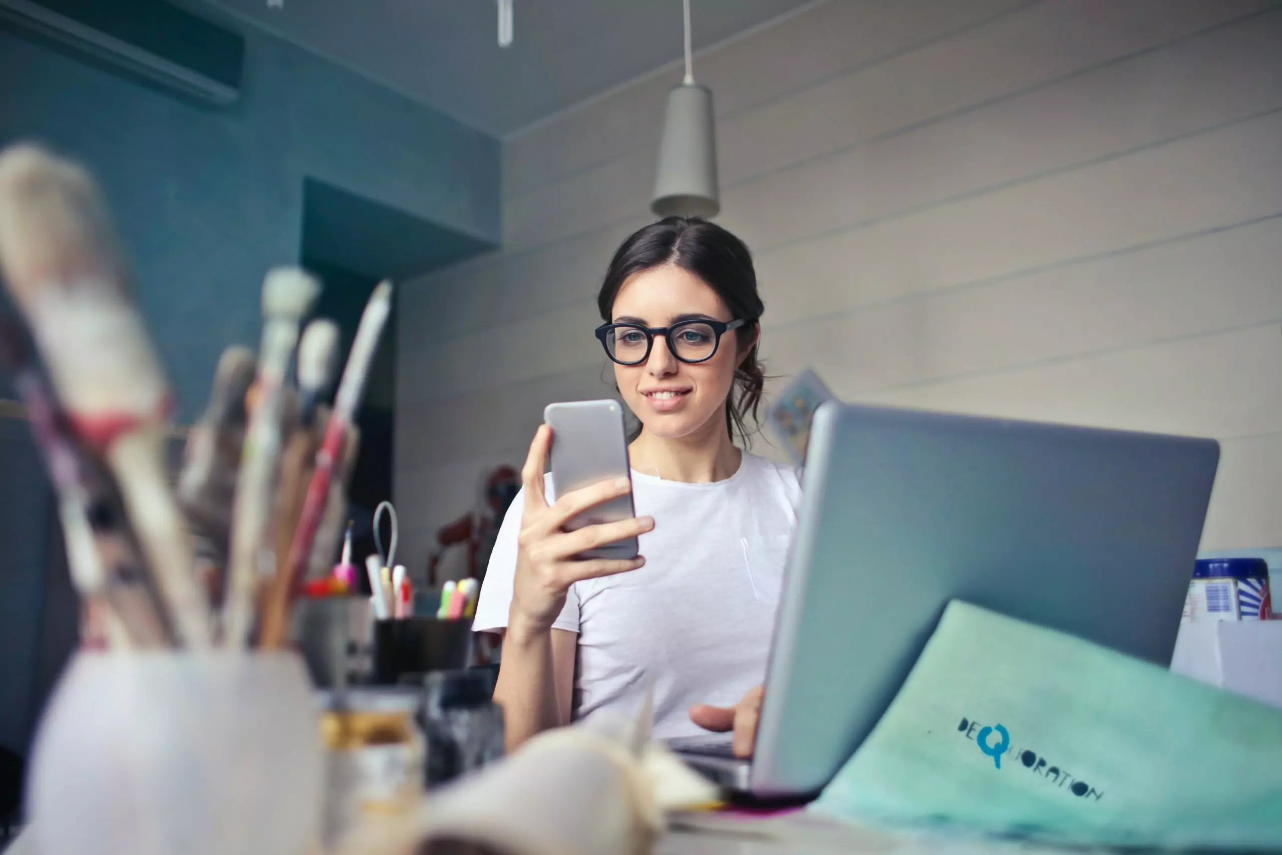 women on computer looking at phone