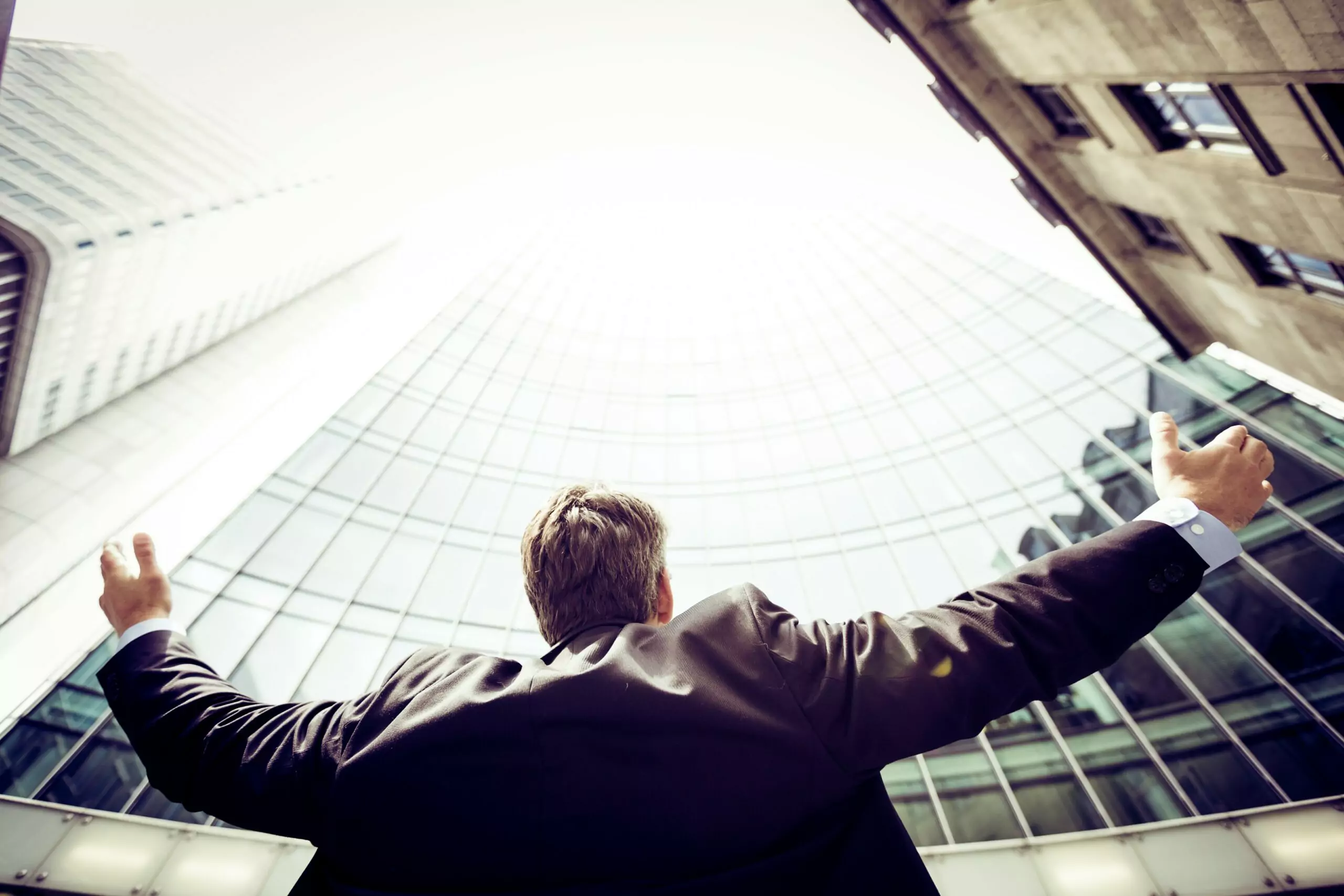 man next to a building holding his arms out
